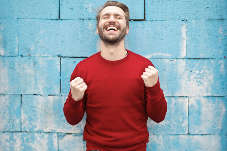 man in front of blue wall happy and confident